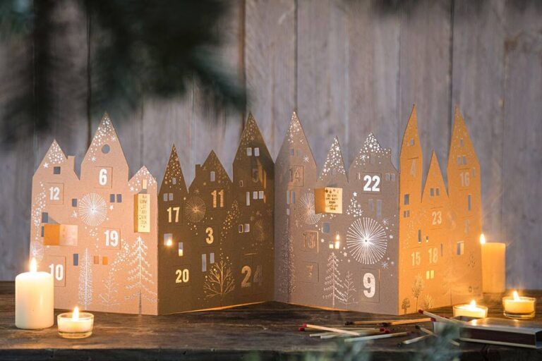 Een adventskalender staat versierd met kaarsen en lichtjes op een ladekast.