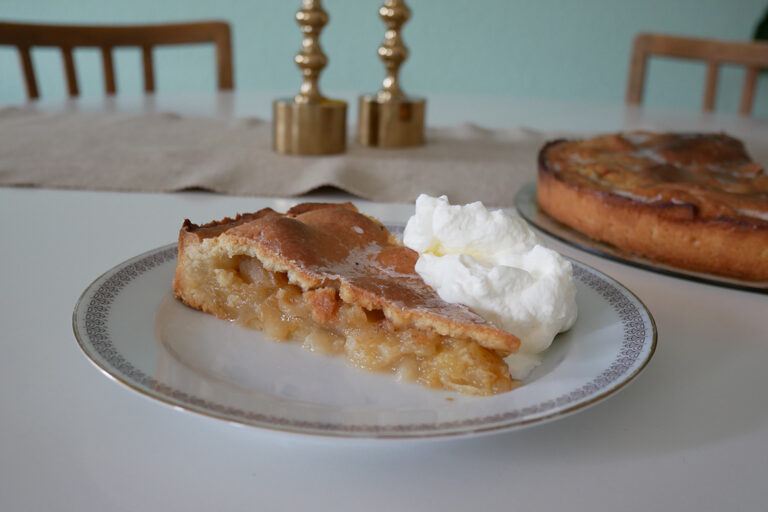 Een stuk appeltaart met een portie room staat klaar op tafel.