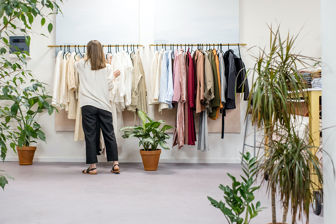 Vrouw staat voor een kledingrek in een kledingwinkel.