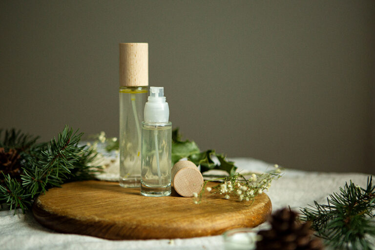 De zelfgemaakte deodorantspray zit in twee spuitflessen van verschillende groottes op een houten plank.