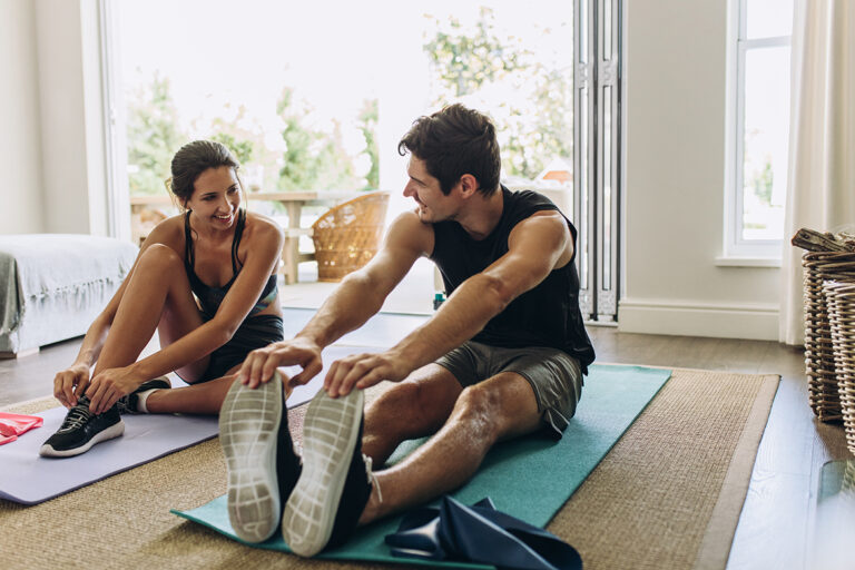 Man en vrouw zitten elk op een mat in de woonkamer.