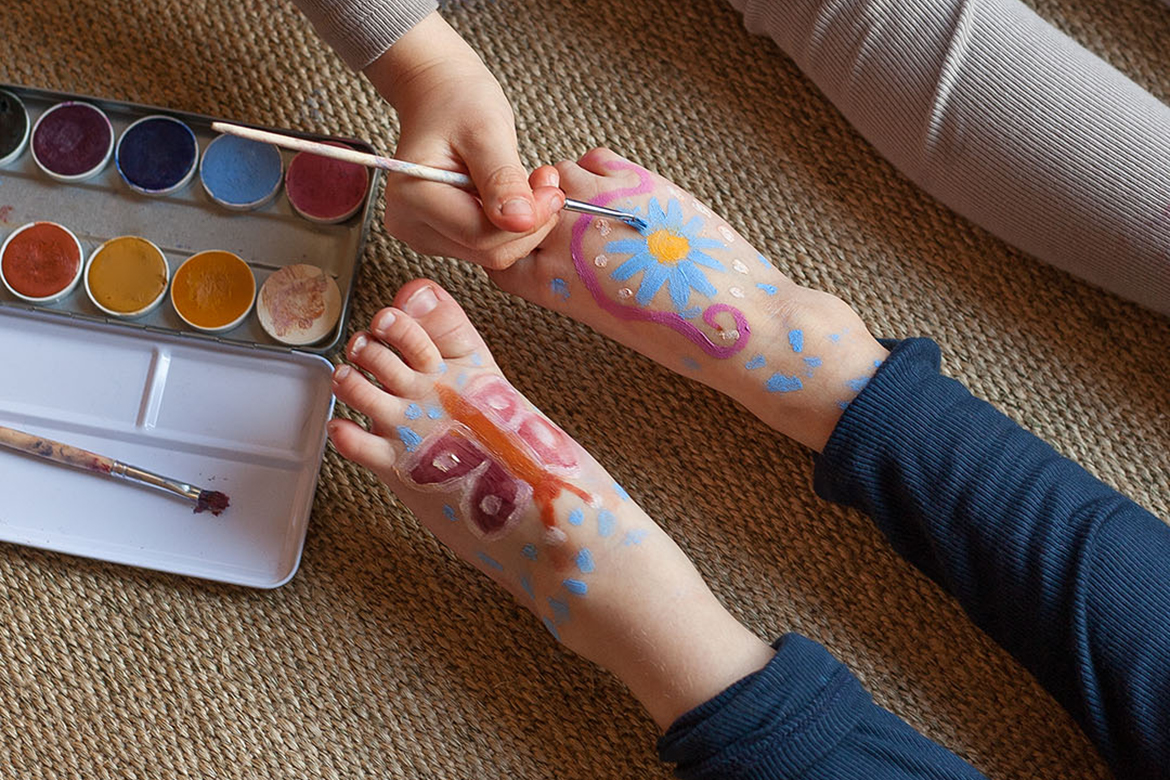 Kindervoeten worden met een penseel met kleurrijke motieven beschilderd