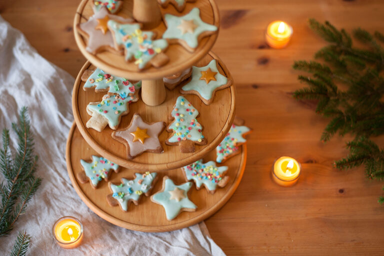 Kleurrijke taaitaai-koekjes liggen op een houten etagère.