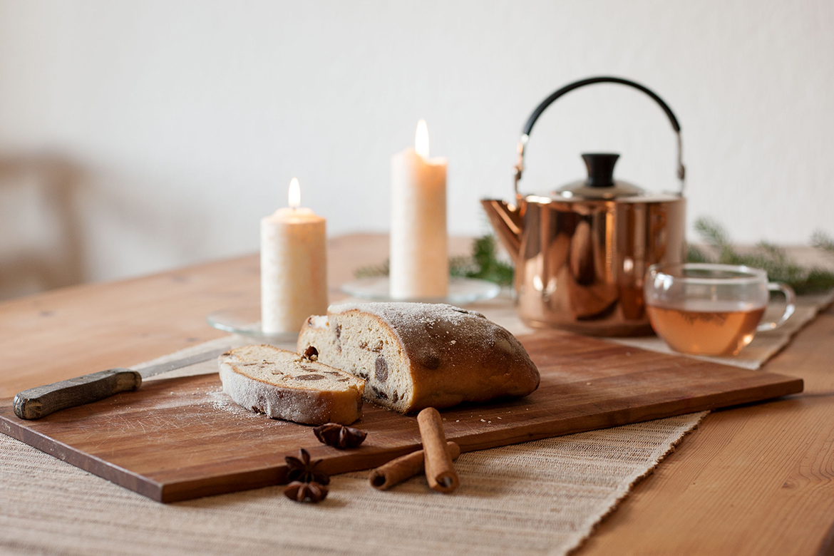 Een veganistisch kerstbrood ligt gesneden op een houten plank op tafel.