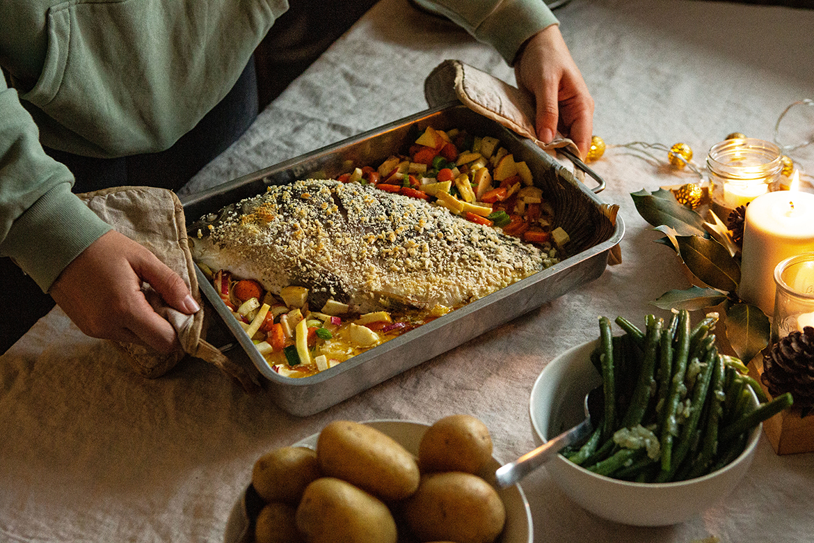 De kerstkarper wordt op tafel gezet in een ovenschaal met de bijgerechten er al op.