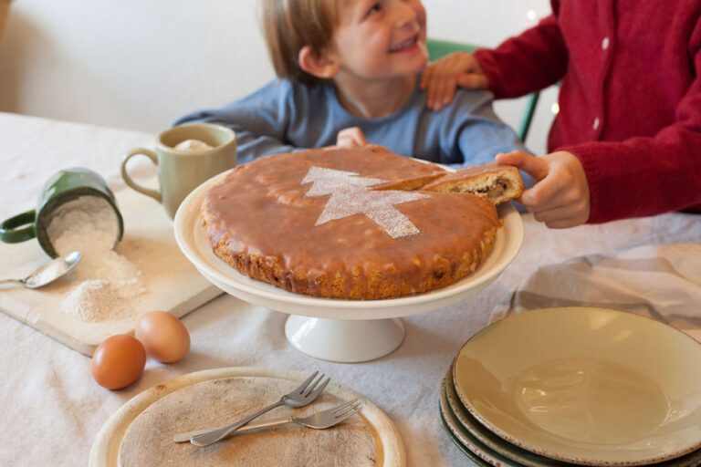 Twee kinderen snoepen van de cake die voor hen op tafel staat.