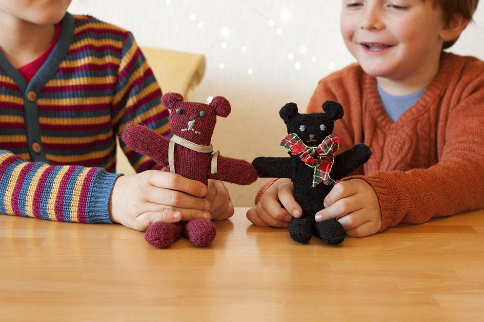 Twee kleine kinderen spelen met teddyberen gemaakt van oude handschoenen.