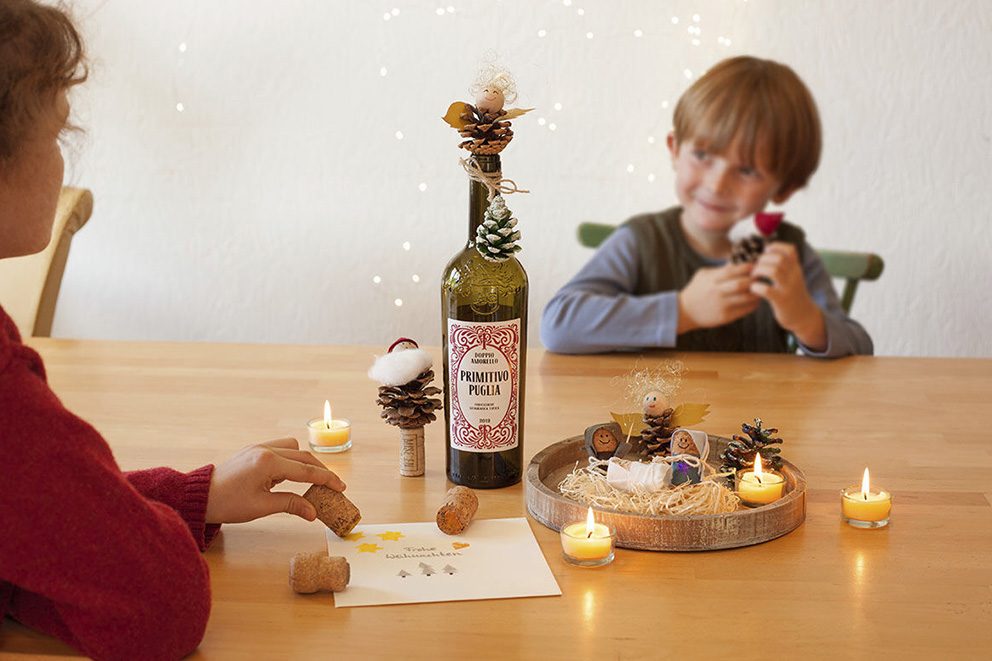 Twee kleine kinderen zitten tegenover elkaar aan een tafel en spelen en knutselen met kurken.