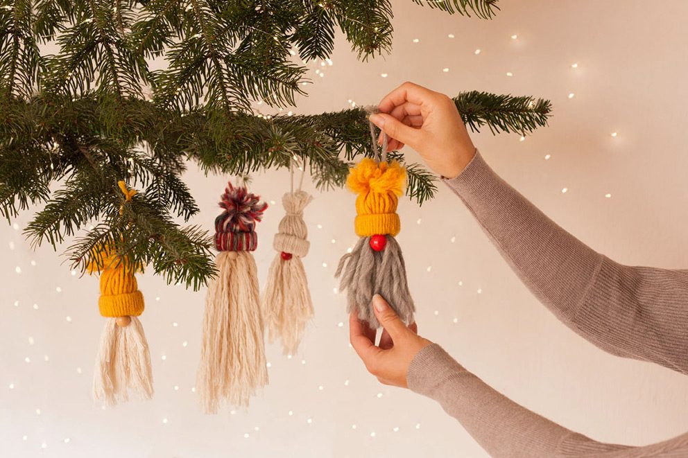 De kleine kerstkabouters worden door een vrouw opgehangen als boomversiering.