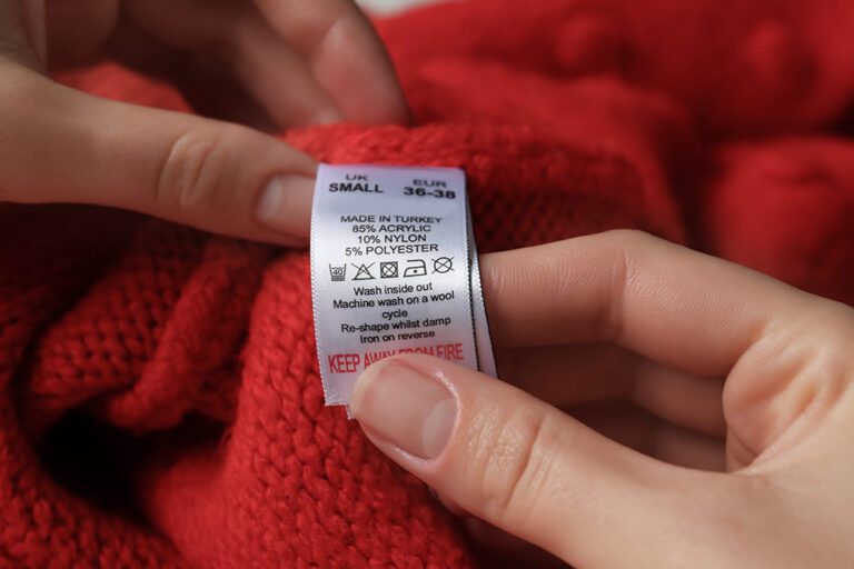 Op het etiket van een rode trui staan de materialen vermeld die microplastics in de kleding kunnen aantonen.