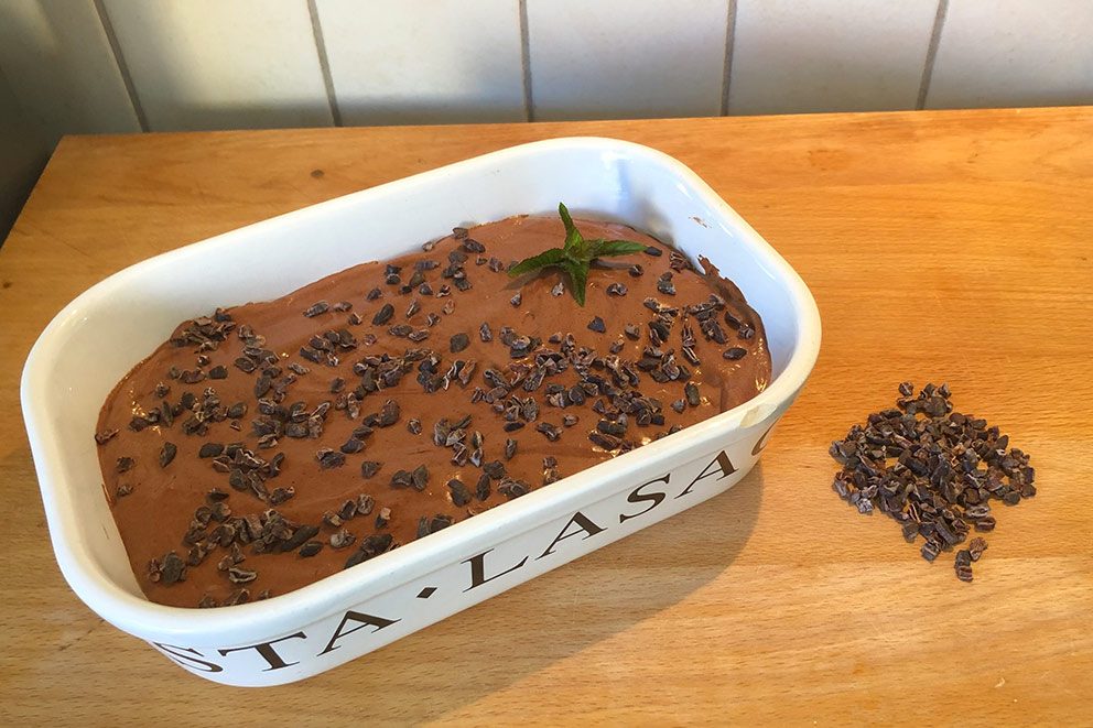 De bereide vegan chocolademousse staat op een houten plank in de keuken.