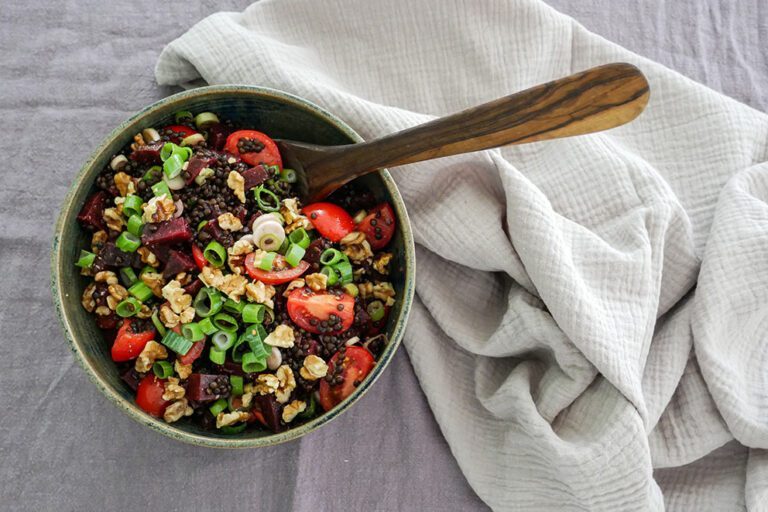 Een schaal linzensalade staat op een gedekte tafel.