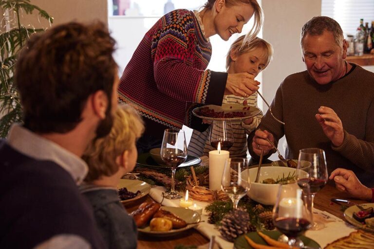 Een familie geniet van het kerstdiner, de moeder schept eten op het bord van haar zoon.