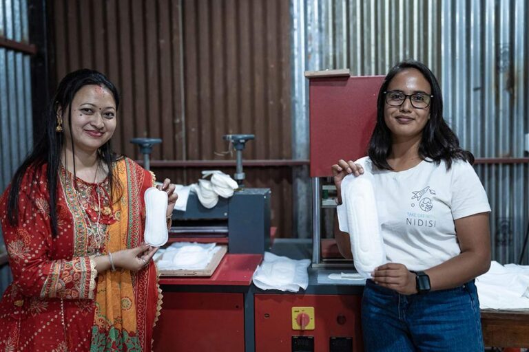 Twee vrouwen houden composteerbaar maandverband van het menstruatieproject voor de camera.