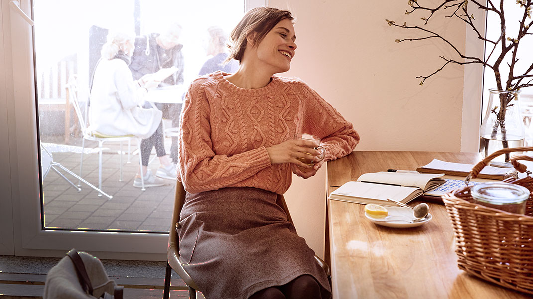 Vrouw in een zachte bio-wollen trui drinkt een kop thee