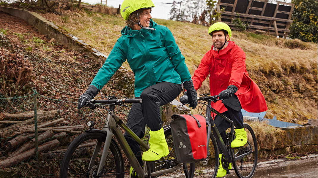 Vrouw en man dragen weerbestendige fietskleding op de fiets.