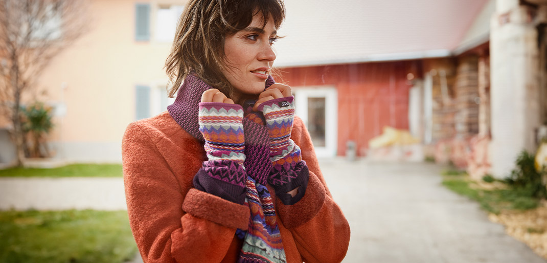 Vrouw warm ingehuld in de winter met gebreide sjaal en armwarmers