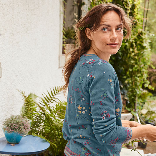 Vrouw in een biologisch zijden shirt zit in de woonkamer en speelt een bordspel