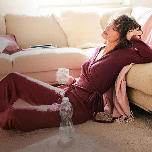 Vrouw in een duurzame pyjama zit op een vloerkleed