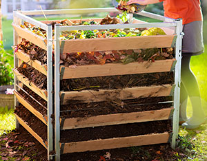 Houten compostbak met metalen frame wordt gevuld