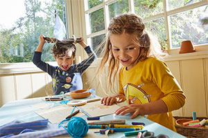Jongen en meisje dragen een shirt met lange mouwen van bio-katoen en zijn aan het knutselen en spelen.