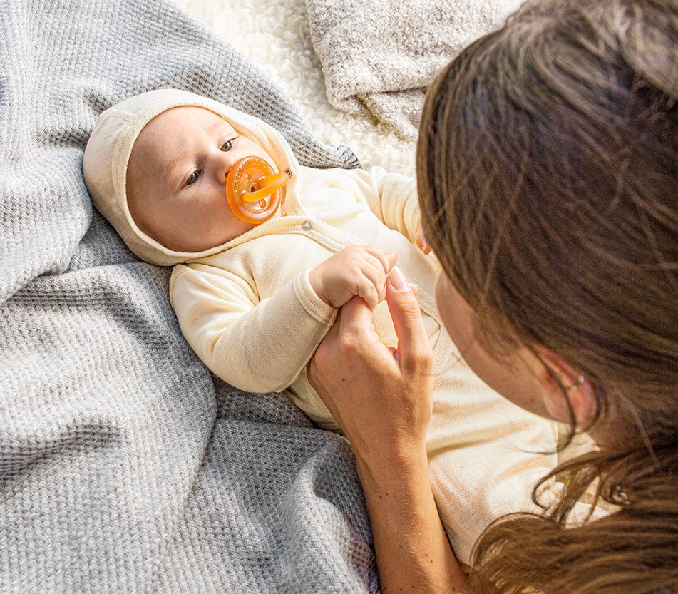 Baby in de kleding van de basis uitzet samen met zijn moeder