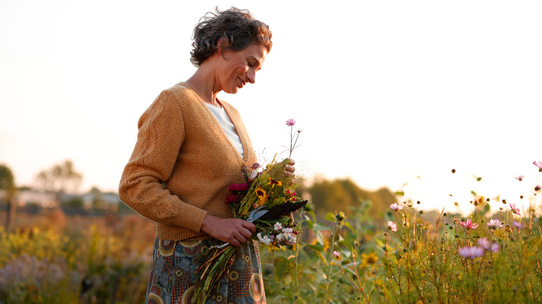 Vrouw plukt bloemen op een bloemenveld.