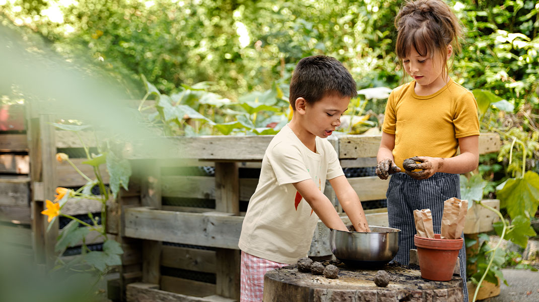 Kinderen tuinieren tussen verschillende moestuinbakken.