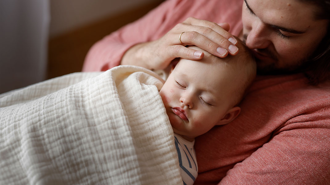 Baby slaapt onder een bio-hydrofieldoek op de buik van de vader