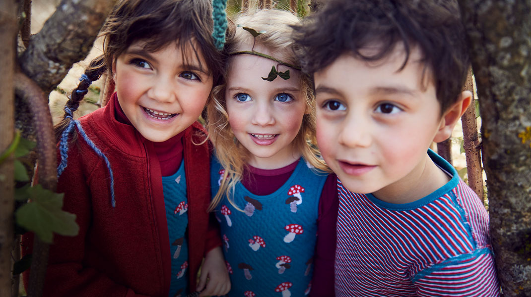 Kinderen in bio-mode van Waschbär trekken gekke gezichten achter het raam van een plantenkas.