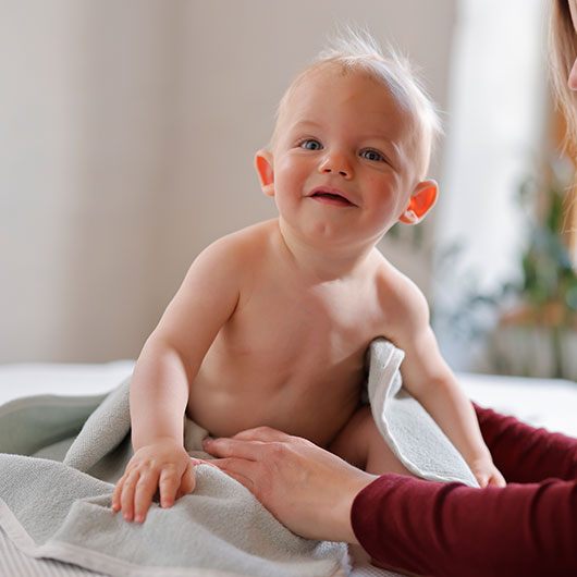 Baby in een zachte bio-handdoek wordt door de moeder vastgehouden