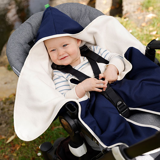 Baby in een wikkeldeken in een Naturkind-kinderwagen van Waschbär