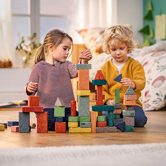 Jongen en meisje spelen met kleurrijke bouwstenen en blokken van kurk