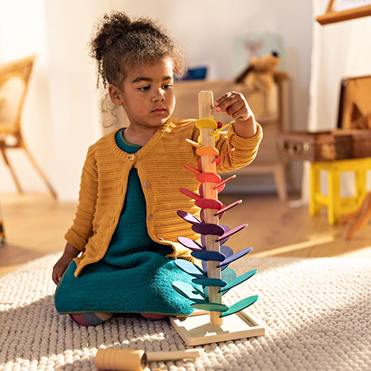 Meisje speelt met knikkers en een kleurrijke klankboom van hout