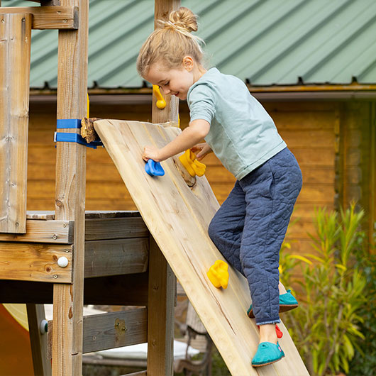 Meisje klimt in de tuin op een klimmuur voor kinderen
