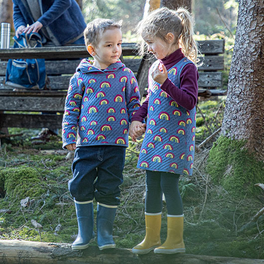 Jongen en meisje in regenboog omkeerbare kleding tijdens een boswandeling