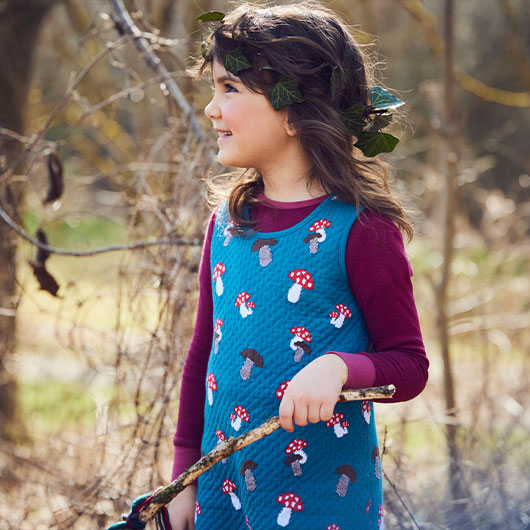 Meisje in omkeerbare jurk met paddenstoelmotief in het bos
