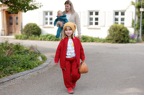 Meisje in een rode walkjas en walkbroek van bio-scheerwol 