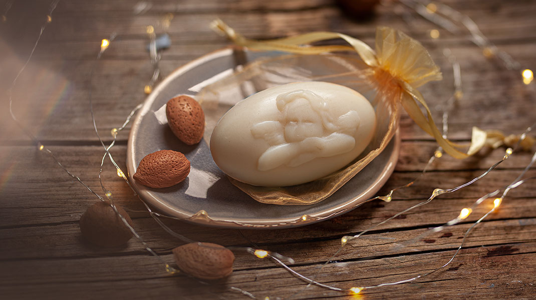 Kerstzeepje in een zeepschaal omgeven door een lichtsnoer en amandelen