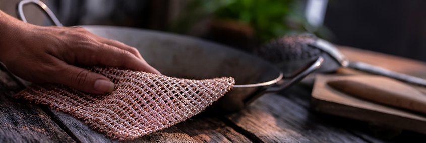 Een koper-schoonmaakdoekje krijgt een ijzeren pan schoon.